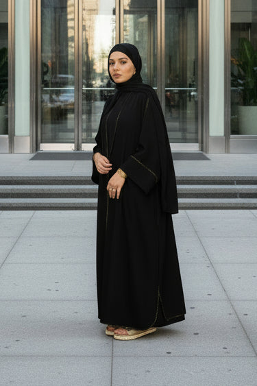 Woman wearing a black abaya against a pink background
